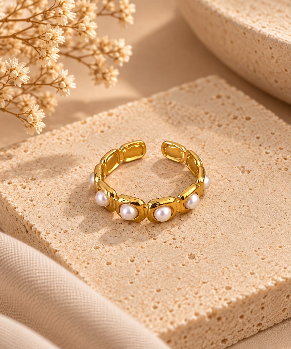 Anillo Nácar dorado de diseño abierto, con sus piezas blancas efecto perla, sobre piedra beige