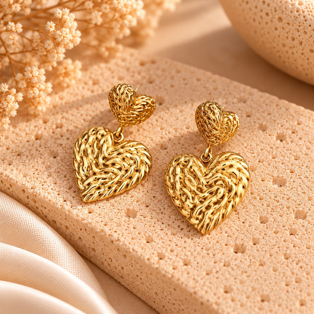 Pendientes Doble Corazón, dos corazones dorados de textura trenzada, uno pequeño arriba y otro grande colgando