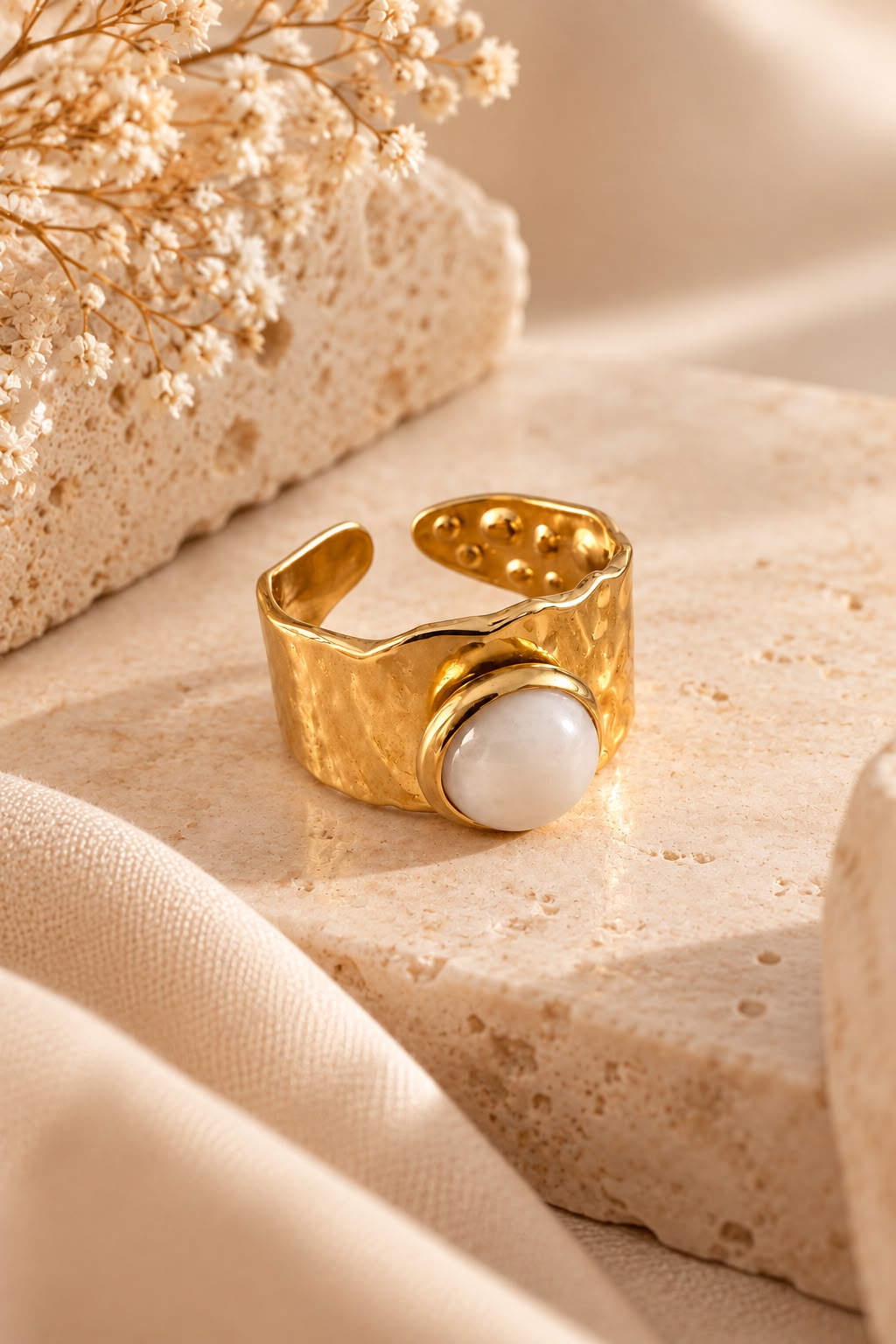 Anillo Cuarzo Rosa con aro martilleado y su piedra natural sobre piedra beige