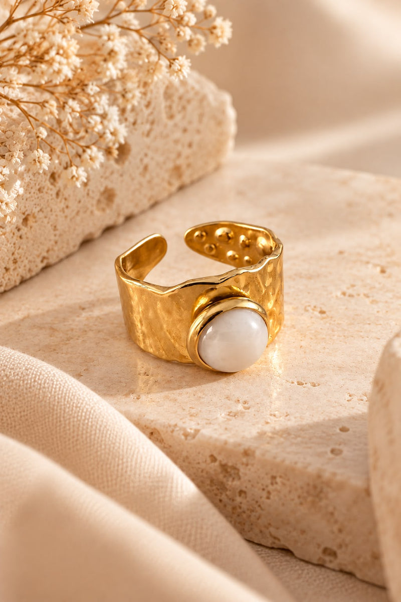 Anillo Cuarzo Rosa con aro martilleado y su piedra natural sobre piedra beige