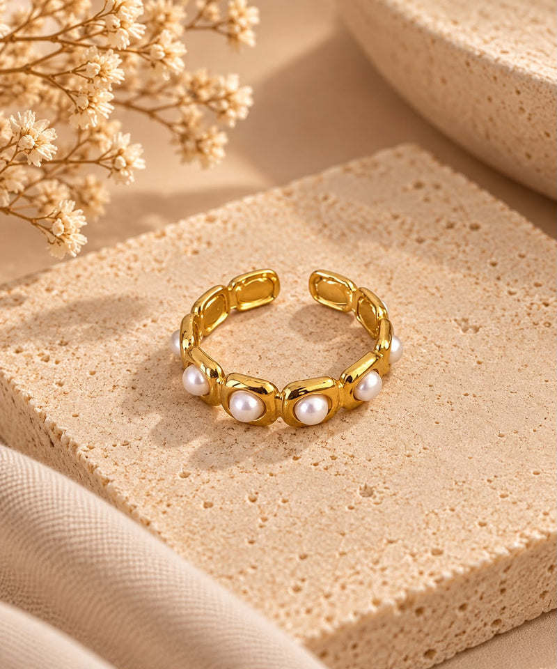 Anillo Nácar dorado de diseño abierto, con sus piezas blancas efecto perla, sobre piedra beige